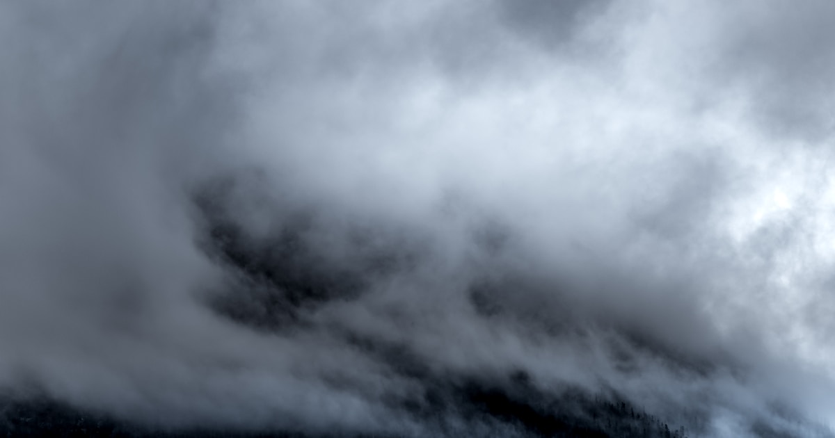 Abstract watercolor of grey fog beginning to lift off a dim ridge — an anxious morning slowly clearing