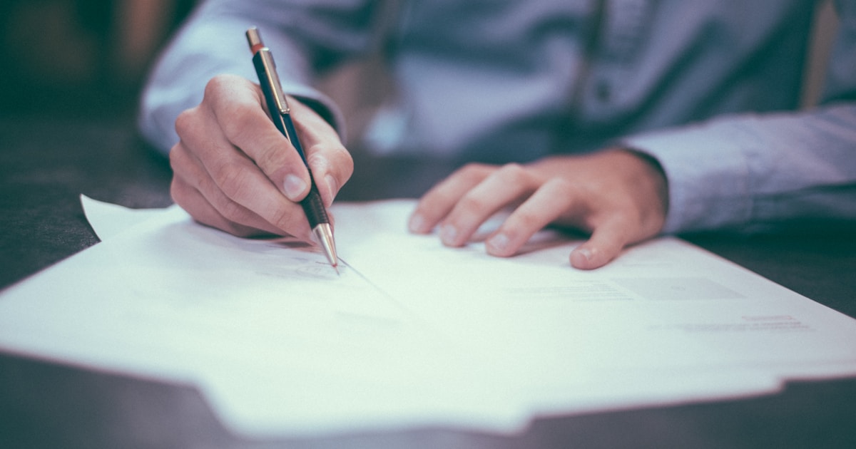 Hands writing notes on a stack of papers — the cheapest insurance against an unexpected rehab bill is the five minutes spent writing every quoted number down