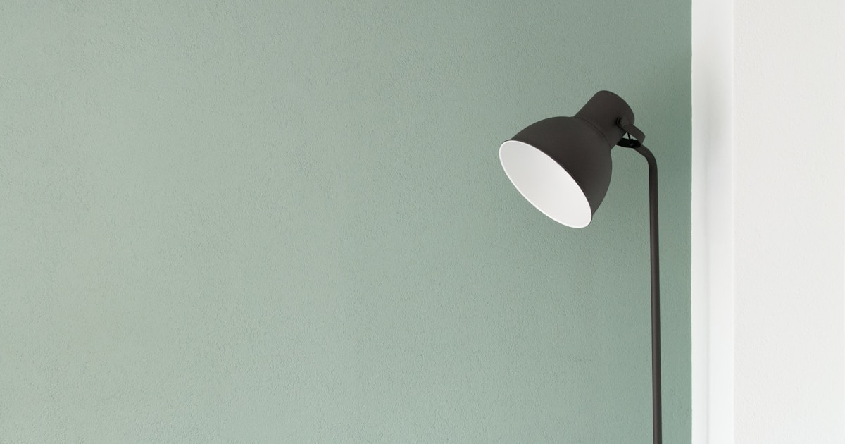 A simple lamp against a sage-green wall in a quiet room — the home environment of outpatient recovery, where treatment fits around ordinary life