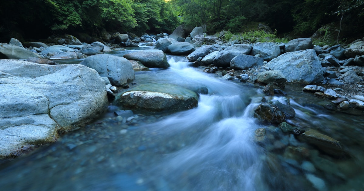 Abstract watercolor of a river easing around smooth rocks into calmer water — cravings being dialed down