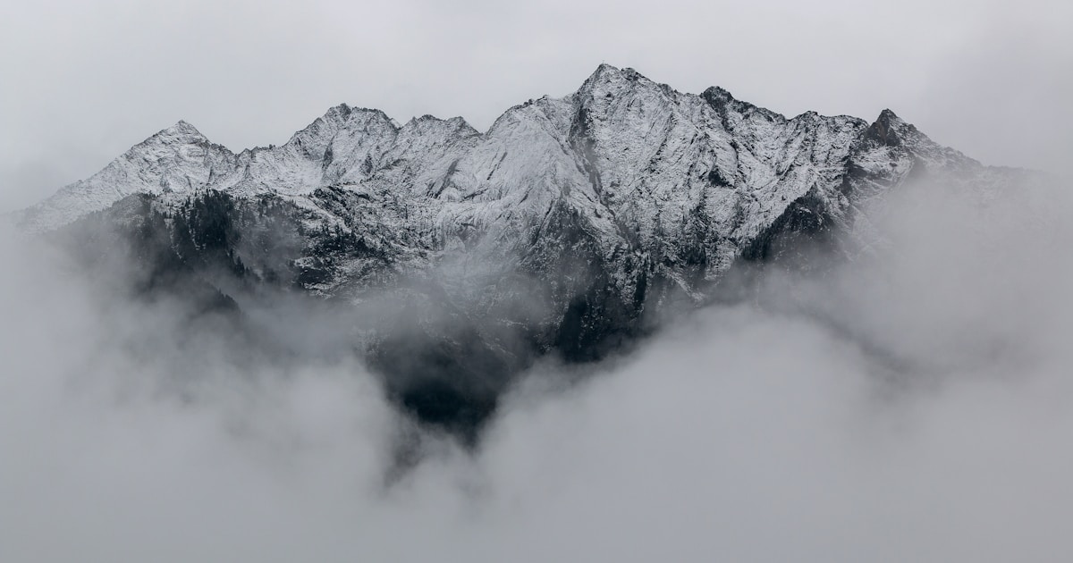 A snowy mountain peak emerging through layered fog — women's recovery often takes a specific path shaped by the particular patterns of women's addiction, trauma history, and caregiver responsibilities