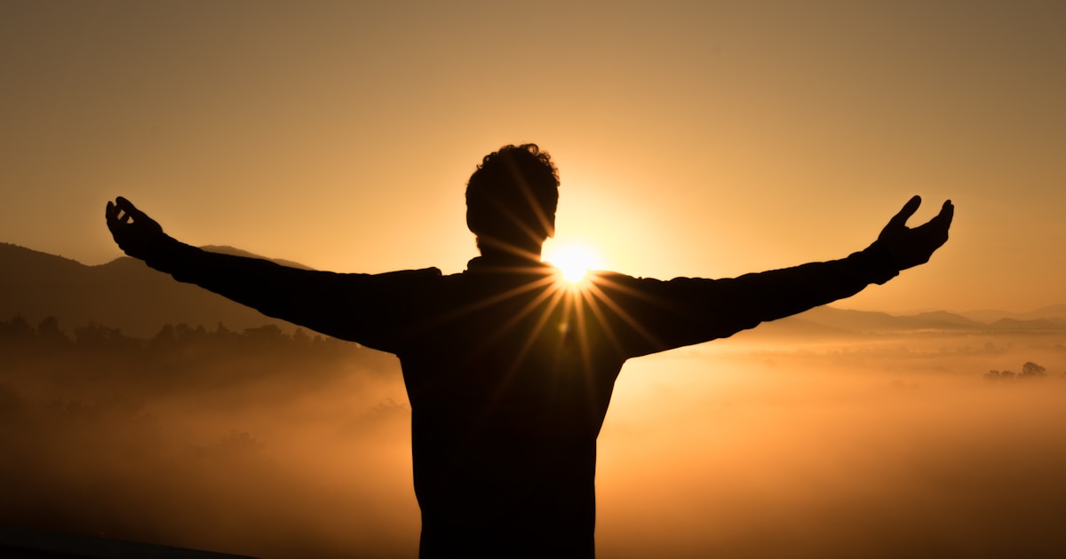 A silhouette against a misty mountain sunrise — the moment after the loving conversation, when something quiet but real begins to shift