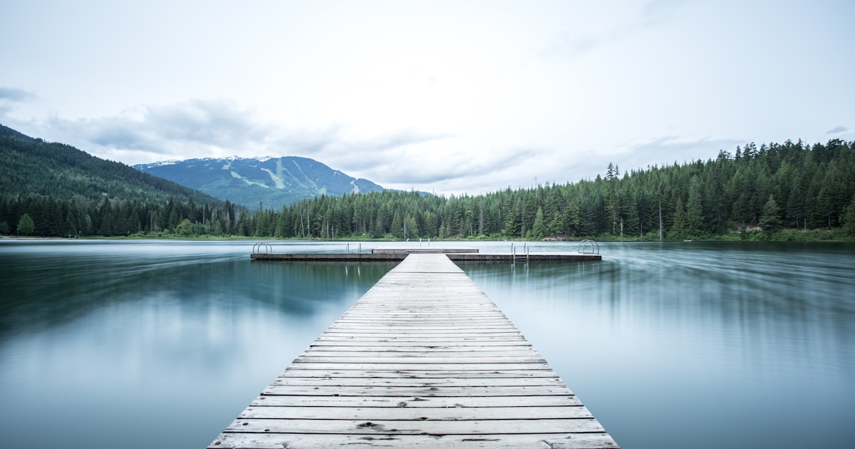 A long wooden dock extending into a calm mountain lake with forested shores — Xanax recovery is the long quiet work of tapering down while building the anxiety skills the original prescription was treating